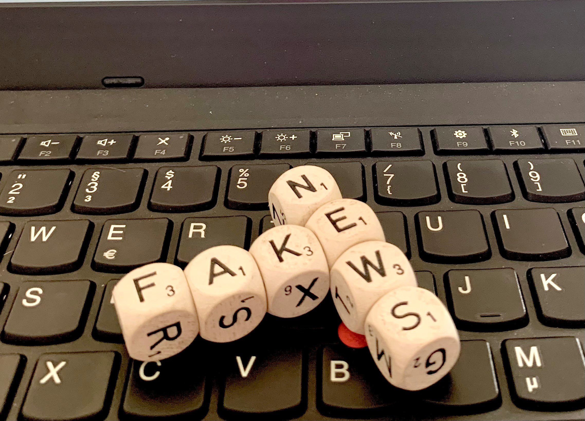 Symbolfoto: Buchstabenwürfel liegen auf einer Computertastatur. Sie formen die Wörter Fake News.