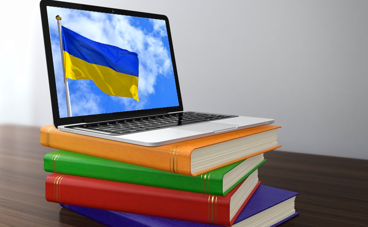 Foto: Laptop, der eine Ukraine-Flagge zeigt, auf einem Bücherstapel