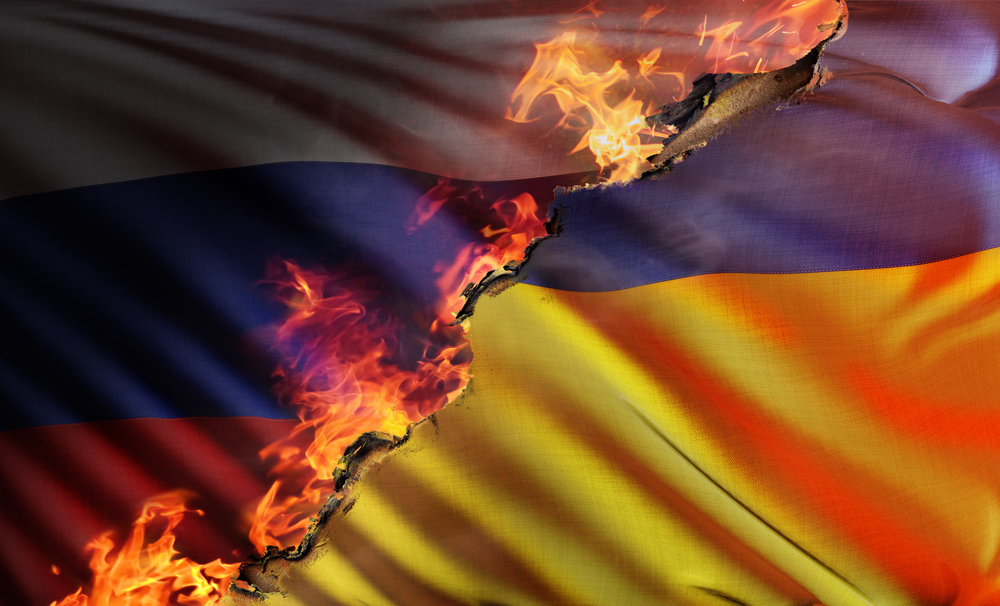 Foto: Russisches und Ukrainische Flagge, zwischen denen ein brennender Riss bestezt