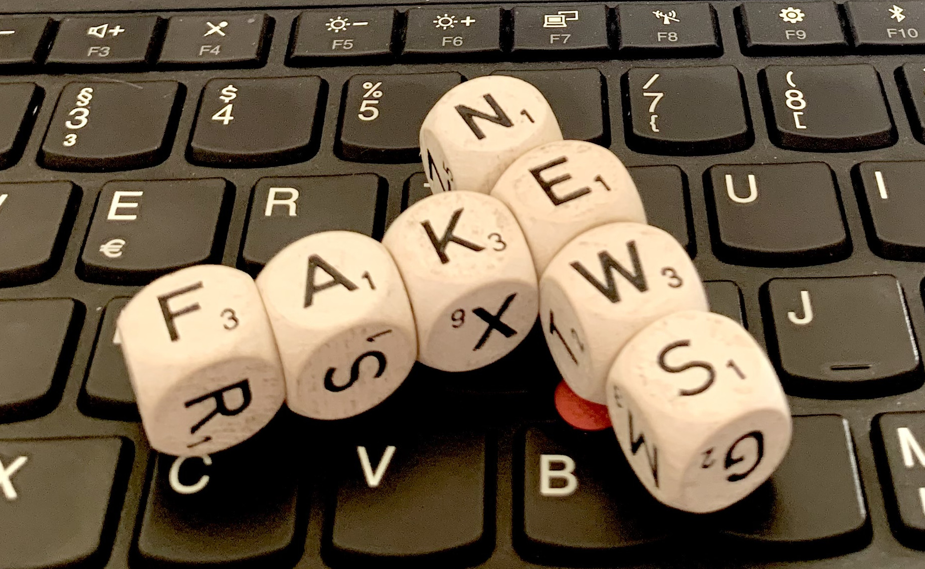 Foto: Scrabble-Steine, die die Wörter FAKE NEWS bilden, auf einer Computertastatur