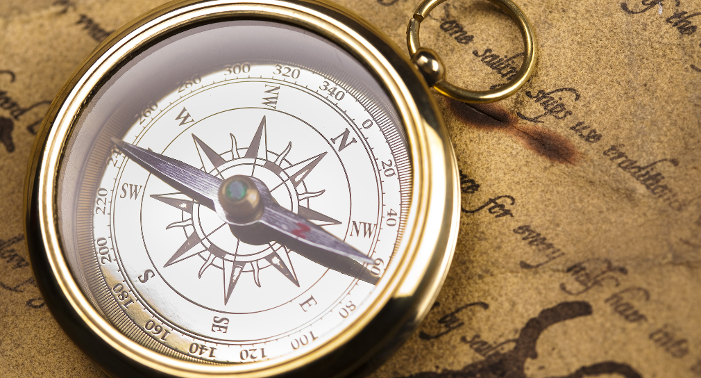 Symbolbild für berufliche Orientierung: Foto eines Taschen-Kompasses, der auf einem alten Pergamentbrief liegt