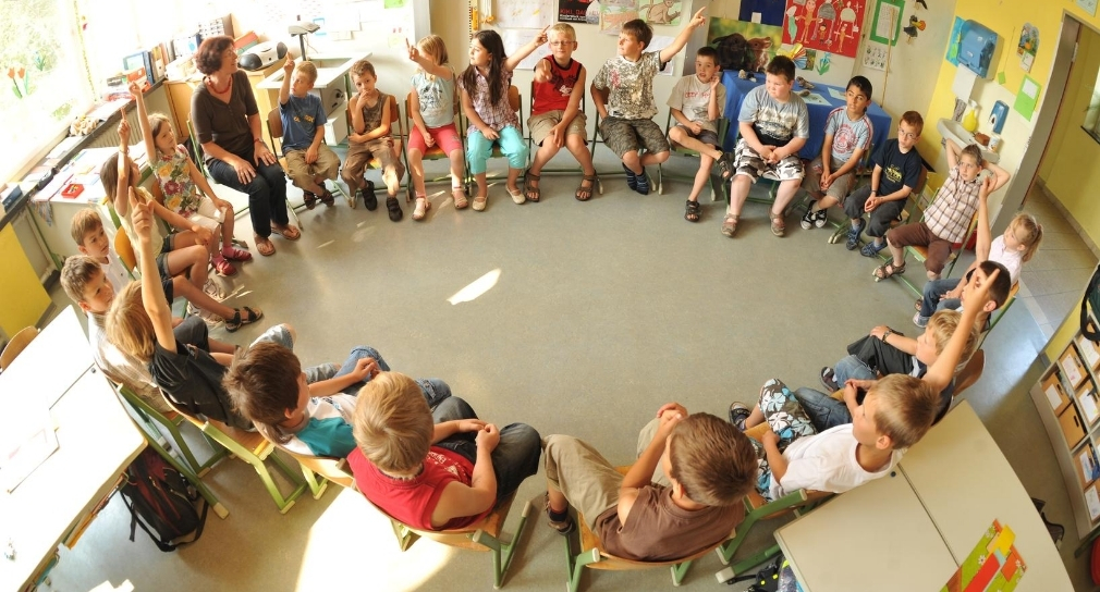 Foto: Schulklasse mit Lehrerin im Stuhlkreis