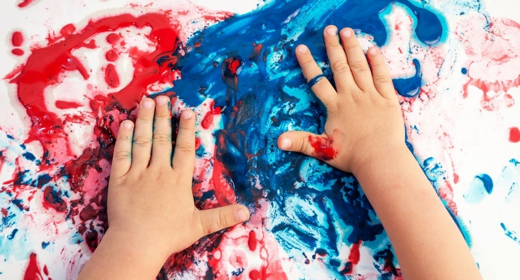 Foto: Kleinkinderhände verschmieren rote und blaue Farbe