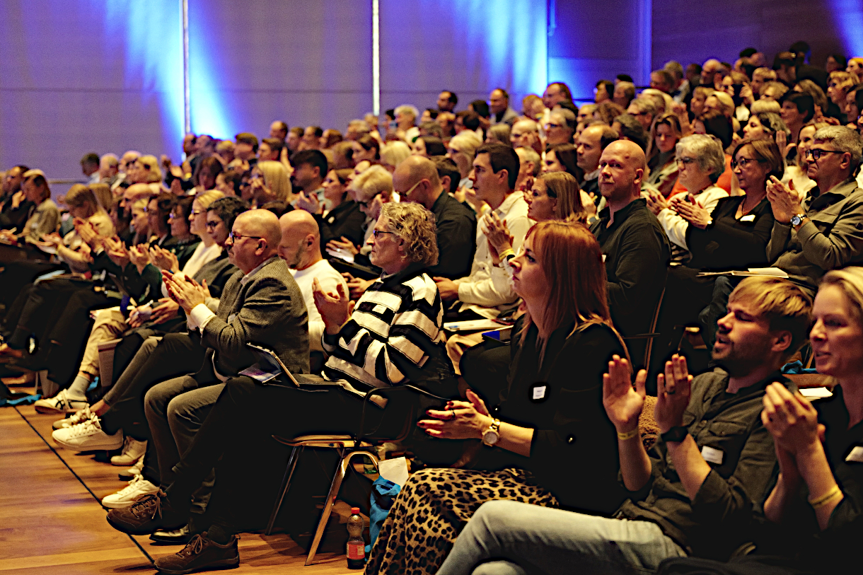 Foto: Großer Applaus der Teilnehmenden für die Vorträge auf dem ersten Schulleitungssymposium Baden-Württemberg in Heilbronn am 11.11.2024. Das Foto zeigt einen Ausschnitt des Publikums, das auf Stühlen sitzt und klatscht. 