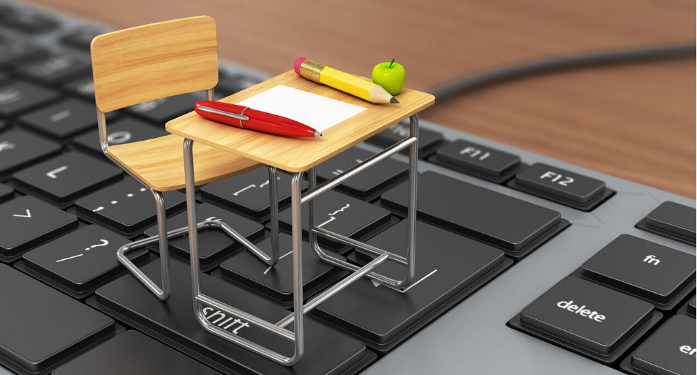 Link zur Seite Digitalisierung (Foto: Schülerpult und -stuhl im Miniaturformat auf Computertastatur) 