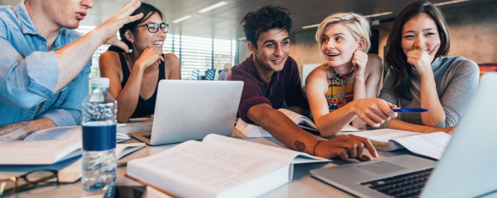 Symbolbild: Lehrkräfte arbeiten zusammen (Foto zeigt sechs Lehrkräfte, die an Laptops arbeiten und miteinander diskutieren)