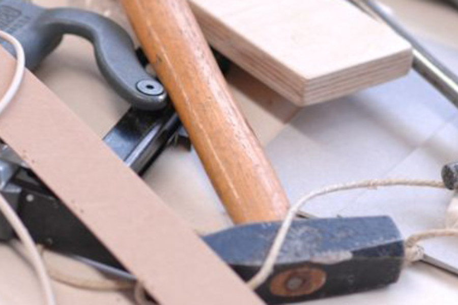 Link zur ZSL-Seite „Technik“; Foto: Ein Hammer, ein Holzbrett und eine Schnur liegen auf einem Tisch.