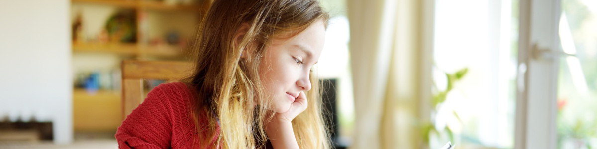Foto: Schülerin am Laptop mit Aufgabenblatt am Esszimmertisch