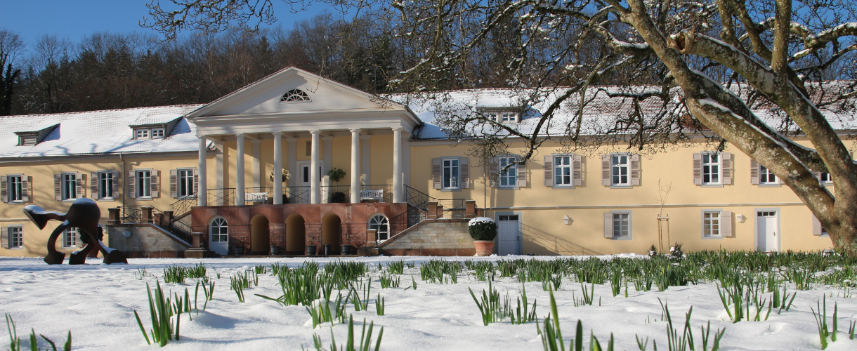 Foto: Blick auf die Fassade von Schloss Rotenfels mit schneebedecktem Garten und Schneeglöckchen