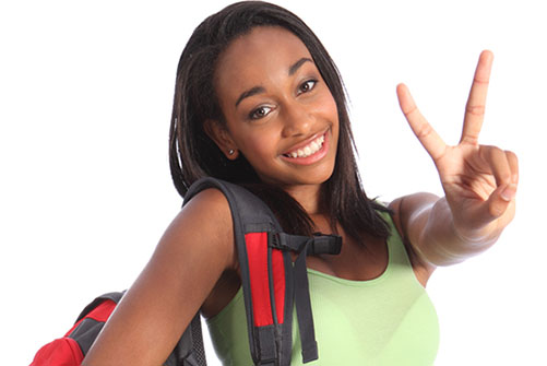 Symbolbild für Sekundarstufe eins (Foto: eine Jugendliche mit Rucksack schaut lächelnd in die Kamera und macht mir ihrer linken Hand ein Victory-Zeichen)