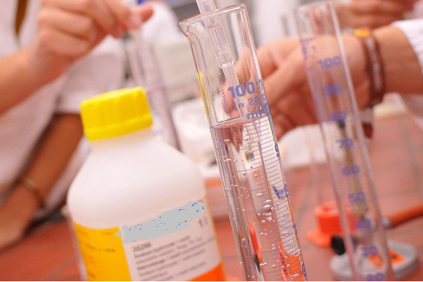 Link zur ZSL-Seite „Chemie“; Foto: Auf einem Experimentiertisch stehen Messzylinder und Chemikalienflaschen.