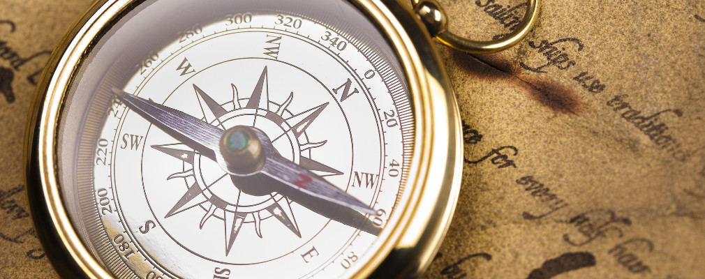 Symbolbild für berufliche Orientierung: Foto eines Taschen-Kompasses, der auf einem alten Pergamentbrief liegt