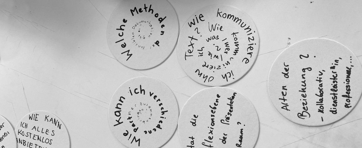 Foto: Runde, handbeschriftete Kärtchen mit Fragen zu Methoden, Kommunikation und Zusammenarbeit sind angeordnet auf einem Tisch. 