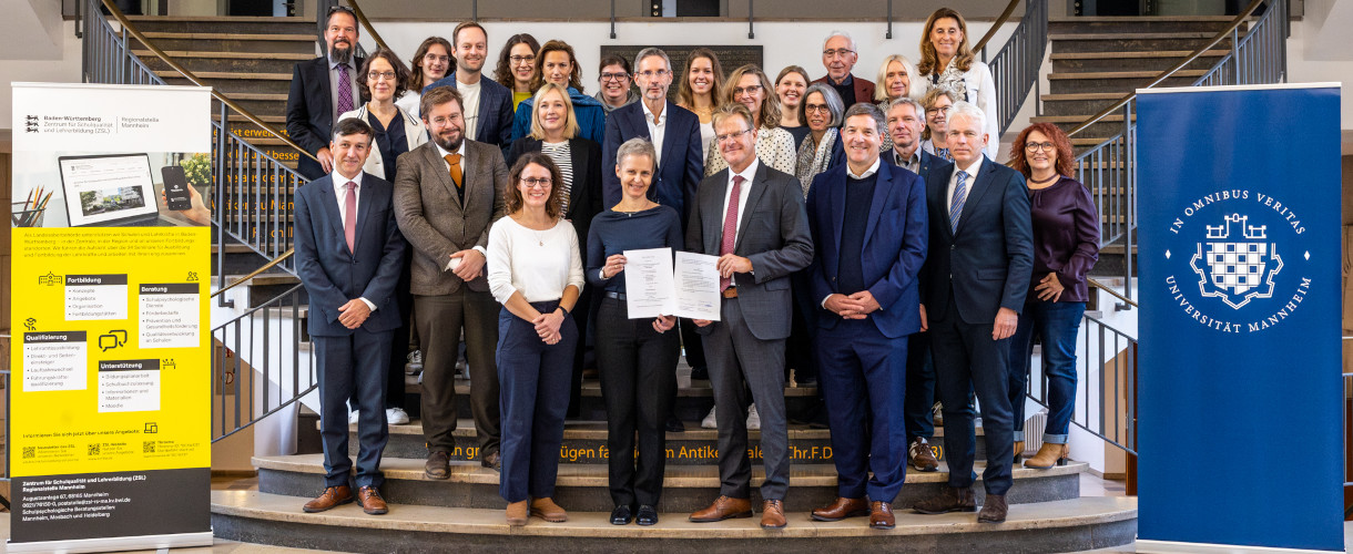 Gruppenfoto anlässlich der Unterzeichnung des Kooperationsvertrags zwischen der Universität Mannheim und dem ZSL am 21. Oktober 2025 (Foto: Mittig in der ersten Reihe stehen Prof. Dr. Cornelia Ruhe, Prorektorin für Studium und Lehre der Universität Mannheim, und Prof. Dr. Thomas Riecke-Baulecke, Präsident des ZSL, und halten die Vertragsblätter in Händen. Insgesamt sind um die 30 Personen zu sehen, die in mehreren Reihen auf einer Treppe stehen. Links von der Treppe steht ein Banner des ZSL, rechts ein Banner der Universität Mannheim.)