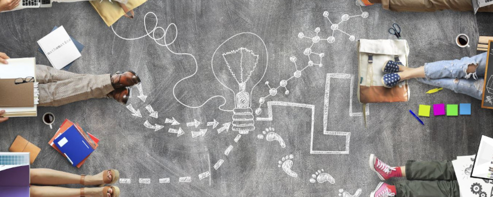 Symbolbild: Vernetzung (Foto zeigt die Beine von je drei sitzenden Personen links und rechts. Auf dem Boden verbinden Kreidestrichlinien die Beine.)