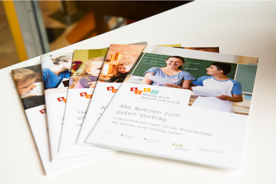 Link; BiSS-Broschüren (Foto: Ein aufgefächerter Stapel von fünf BiSS-Broschüren liegt auf einem weißen Tisch.)