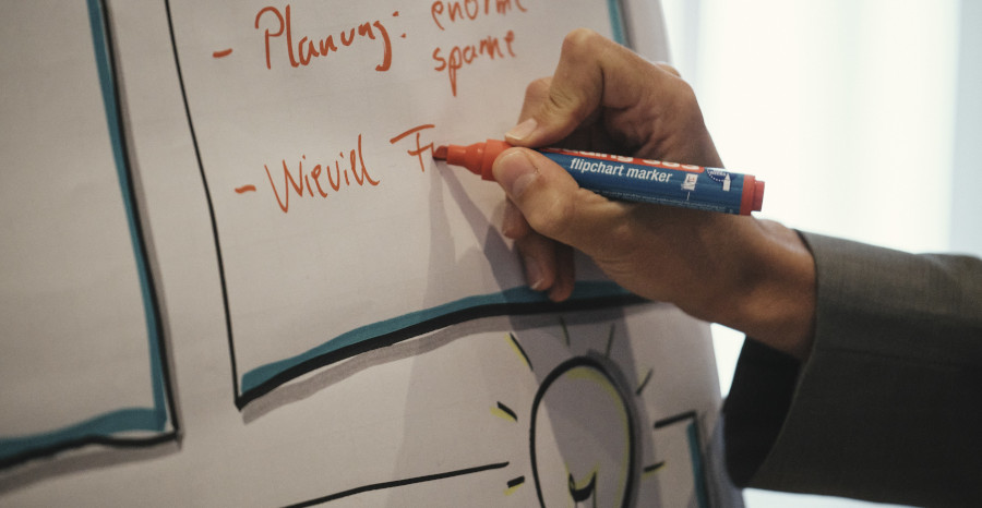 Link zur ZSL-Seite „Wunschkurse“; Foto: Eine Hand schreibt mit Filzstift auf ein Flipchart, das Wort „Planung“ ist lesbar.