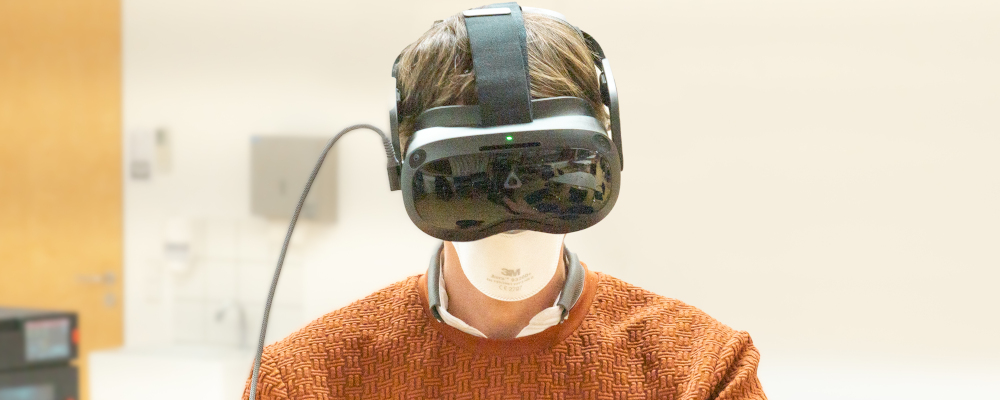 Symbolbild für Virtual Reality (Foto: Kopf und Schultern eines Mannes im orangefarbenen Pulli mit VR-Brille)