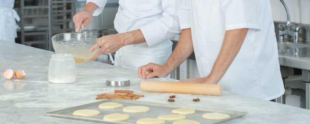 Foto: zwei Personen beim Backen; man sieht nur ihre Arme und Oberkörper