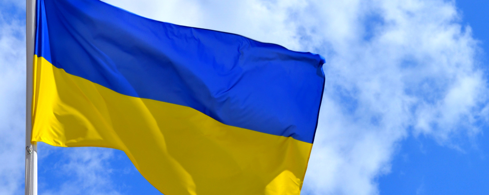 Ukrainische Flagge (Foto: Ukrainische Flagge weht vor leicht bewölktem Himmmel)