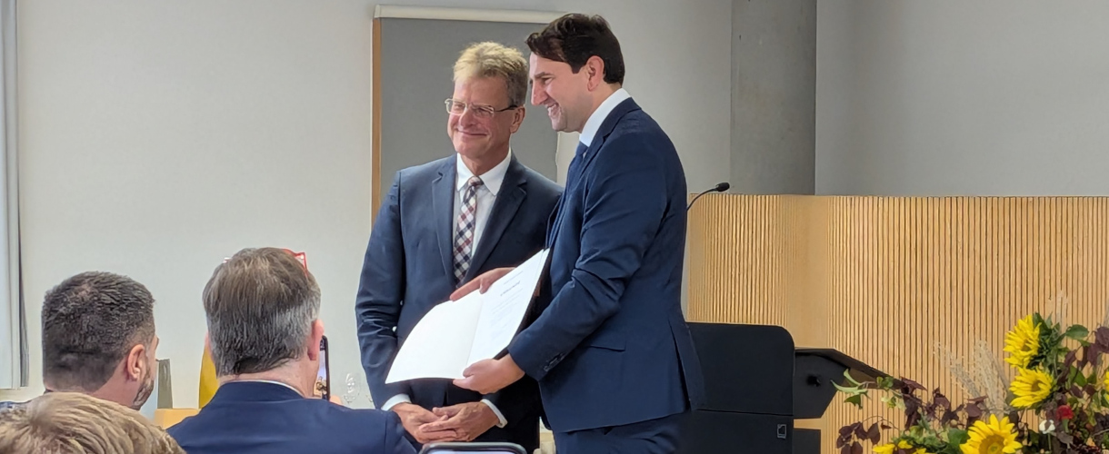Link zur ZSL-Aktuelles-Meldung: 7,5 Jahre ZSL – Rückblick und aktuelle Ergebnisse (Foto: Verabschiedung des ZSL-Präsidenten Professor Doktor Thomas Riecke-Baulecke am 13. Oktober 2026 in der ZSL-Außenstelle Esslingen. Riecke-Baulecke und der baden-württembergische Kultusminister Andreas Jung stehen lächelnd vor einem Rednerpult. Sie schauen in die Runde der sitzenden Gäste. Andreas Jung präsentiert eine Urkunde, die er mit beiden Händen zum Publikum gerichtet vor seinen Oberkörper hält.)