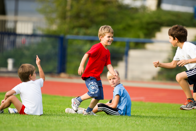 Link zur ZSL-Seite „Schulsport“; Foto: Kinder beim Schulsport auf dem Rasen