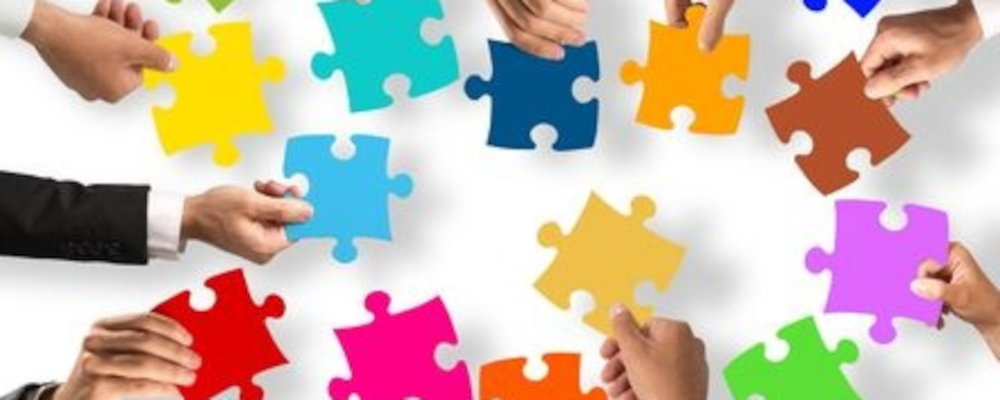 Foto: Hände geben farbige Puzzleteile