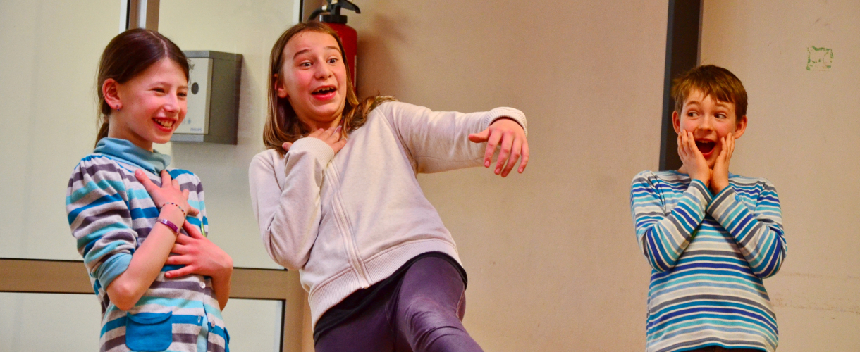 Foto einer Szene: Drei Kinder freuen sich und sind erstaunt.