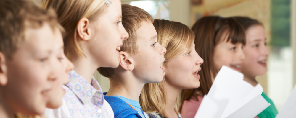 Symbolbild für Musik (Foto: Gruppe von Mädchen und Jungen, die singen und Notenblätter in den Händen halten)