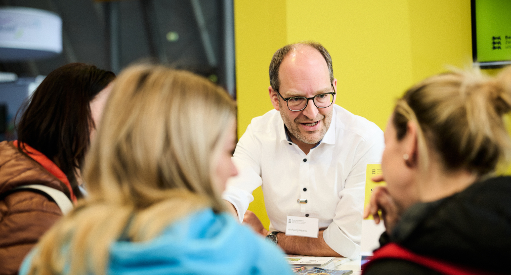 Fotografie: ZSL-Mitarbeitender im Gespräch mit interessierten Messebesucherinnen und -besuchern 