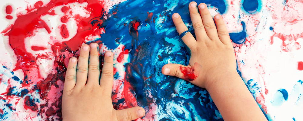 Foto: Kleinkinderhände verschmieren rote und blaue Farbe