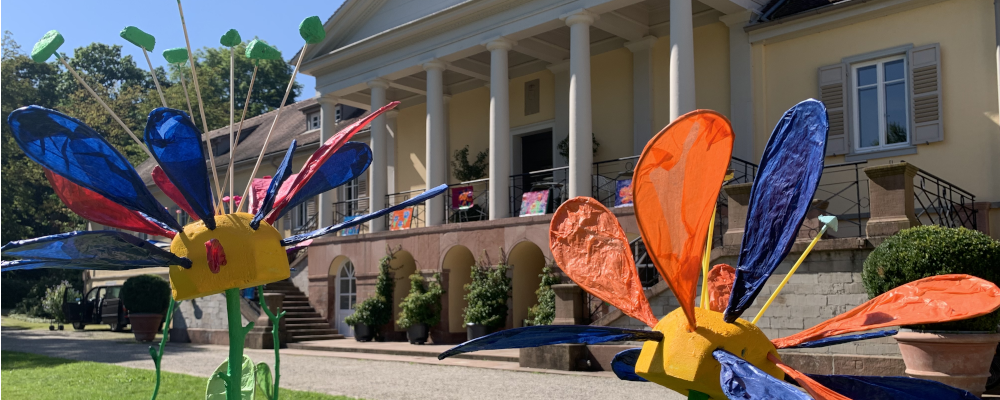 Foto: Kunstinstallation: riesige, bunte Kunstblumen vor dem Gebäude von Schloss Rotenfels