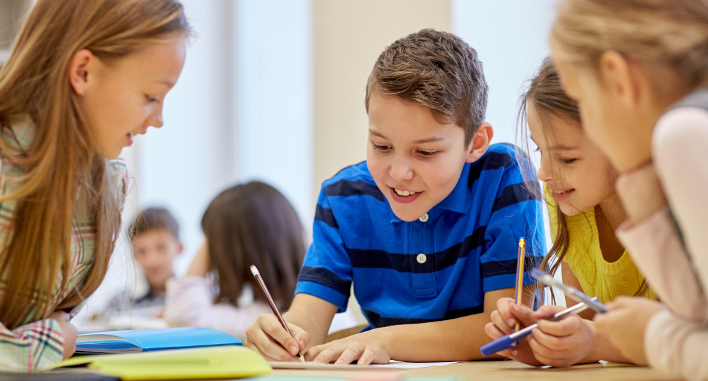 Symbolbild: Unterricht zu Katastrophenschutz (Foto: ein Schüler schreibt, drei Schülerinnen schauen ihm dabei zu)