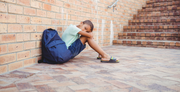 Foto: trauriger Schüler, der auf dem Boden sitzt