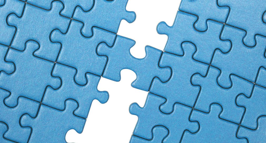 Symbolbild: Foto: Puzzleteile (Zu sehen ist ein Puzzle, das sich aus mehreren blauen Puzzleteile-Reihen zusammensetzt. In der Mitte fehlen drei Teile, und ein Teil verbindet die rechte und linke Hälfte des Puzzles.)