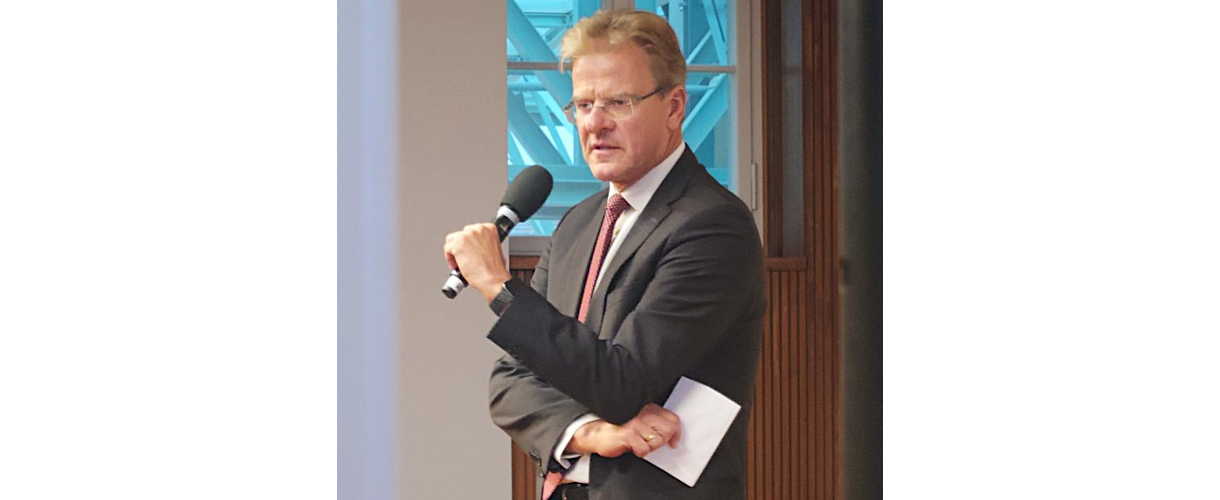 Fachtagung, Berlin 25.09.2025: Foto von Prof. Dr. Thomas Riecke-Baulecke (Er trägt einen grauen Anzug, Krawatte und Brille und spricht ins Mikrofon.)