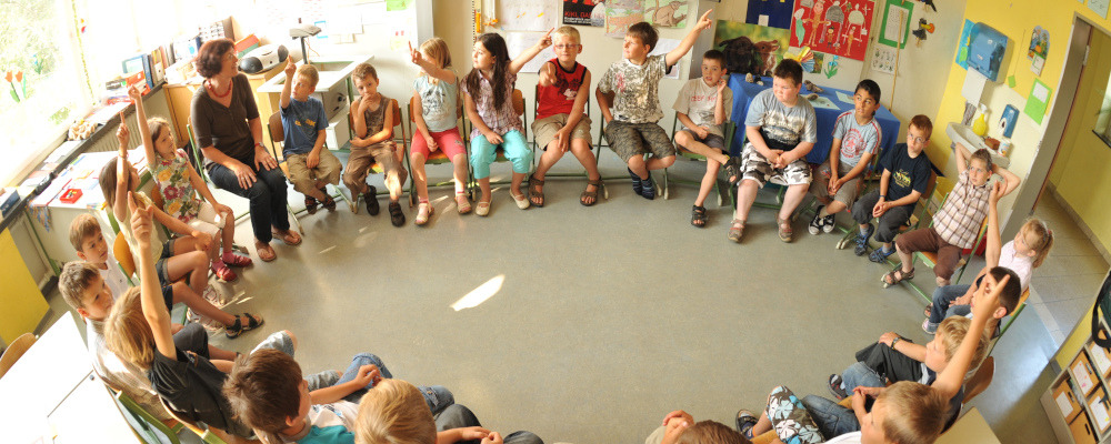 Foto: Schulklasse mit Lehrerin im Stuhlkreis