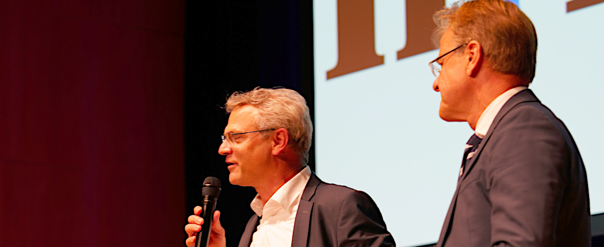 aim-Geschäftsführer Marco Haaf und ZSL-Präsident Prof. Dr. Thomas Riecke-Baulecke begrüßen die Gäste bei der Abendveranstaltung „Mit Visible Learning zum Lernerfolg“ (Heilbronn, 22.09.2025) (Foto: Marco Haaf spricht in das Mikrofon; Prof. Dr. Thomas Riecke-Baulecke steht links von ihm und hört zu)